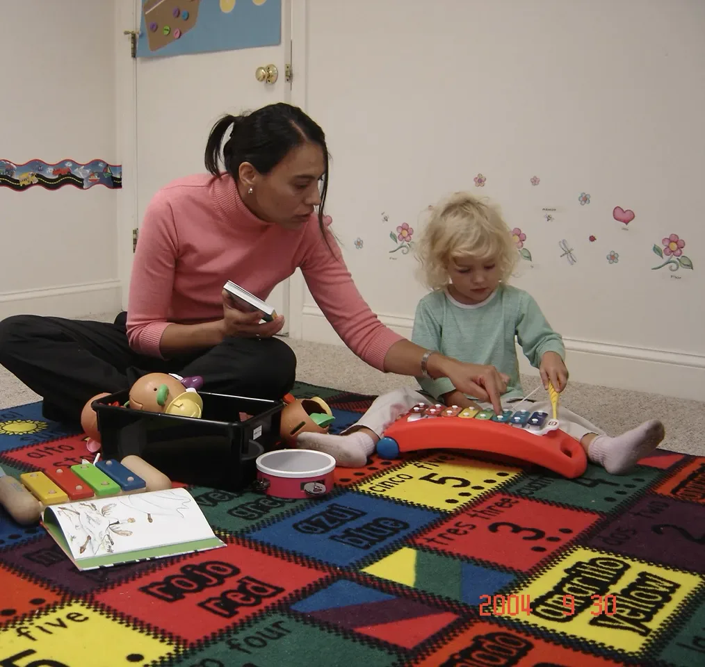 A SELA teacher and a small child play a toy xylophone together during an early Spanish-immersion class.