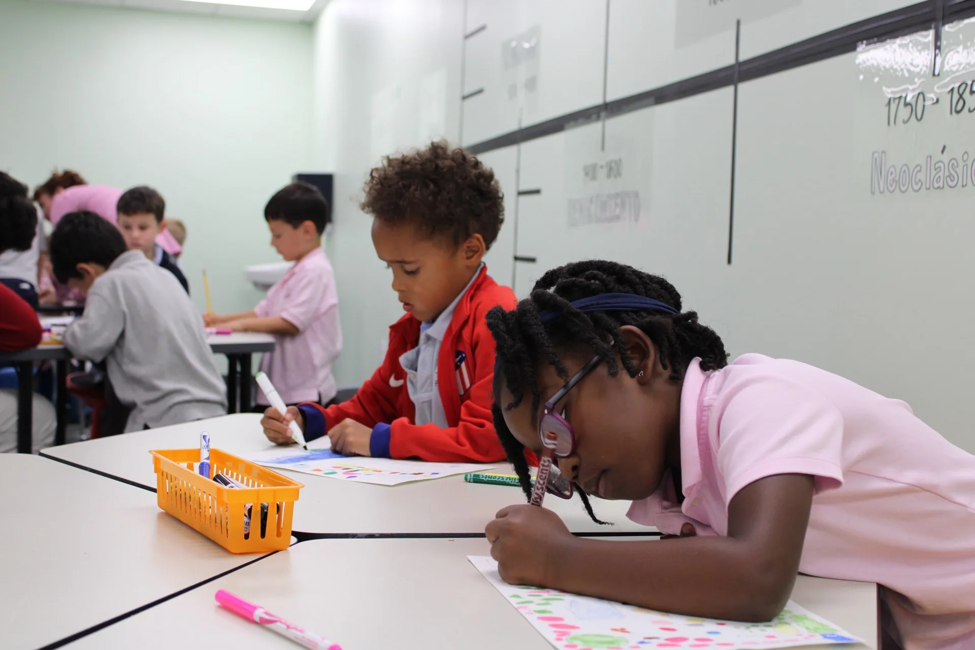 SELA children color and draw at their desks with markers during an art activity.
