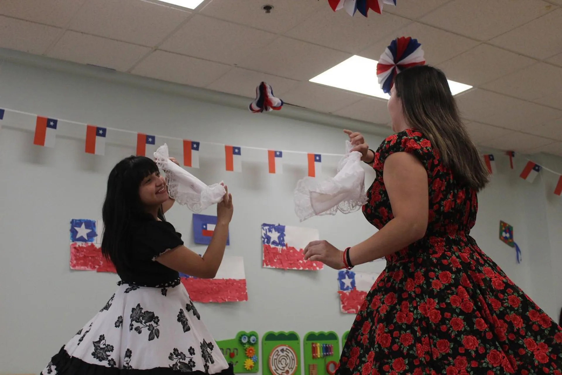 A SELA teacher leaning in to guide a young student through their work